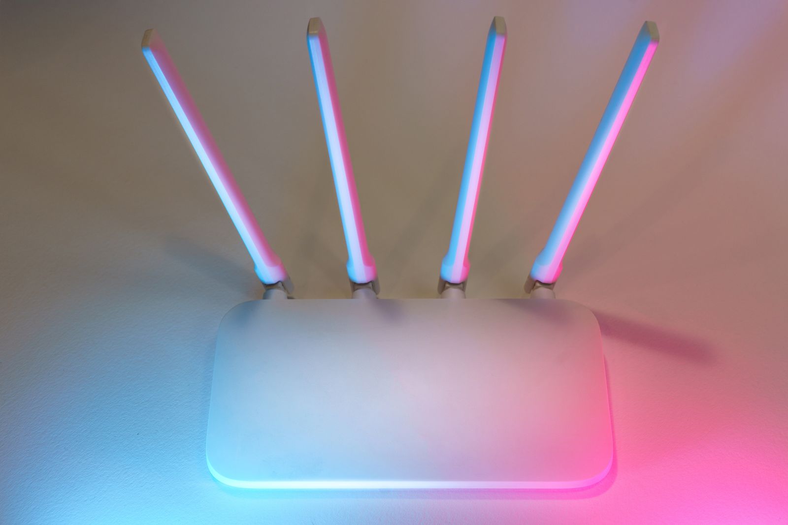 Белый Wi-Fi-роутер с мягкой сине-розовой подсветкой на светлом фоне — иллюстрация к разбору mesh Wi-Fi