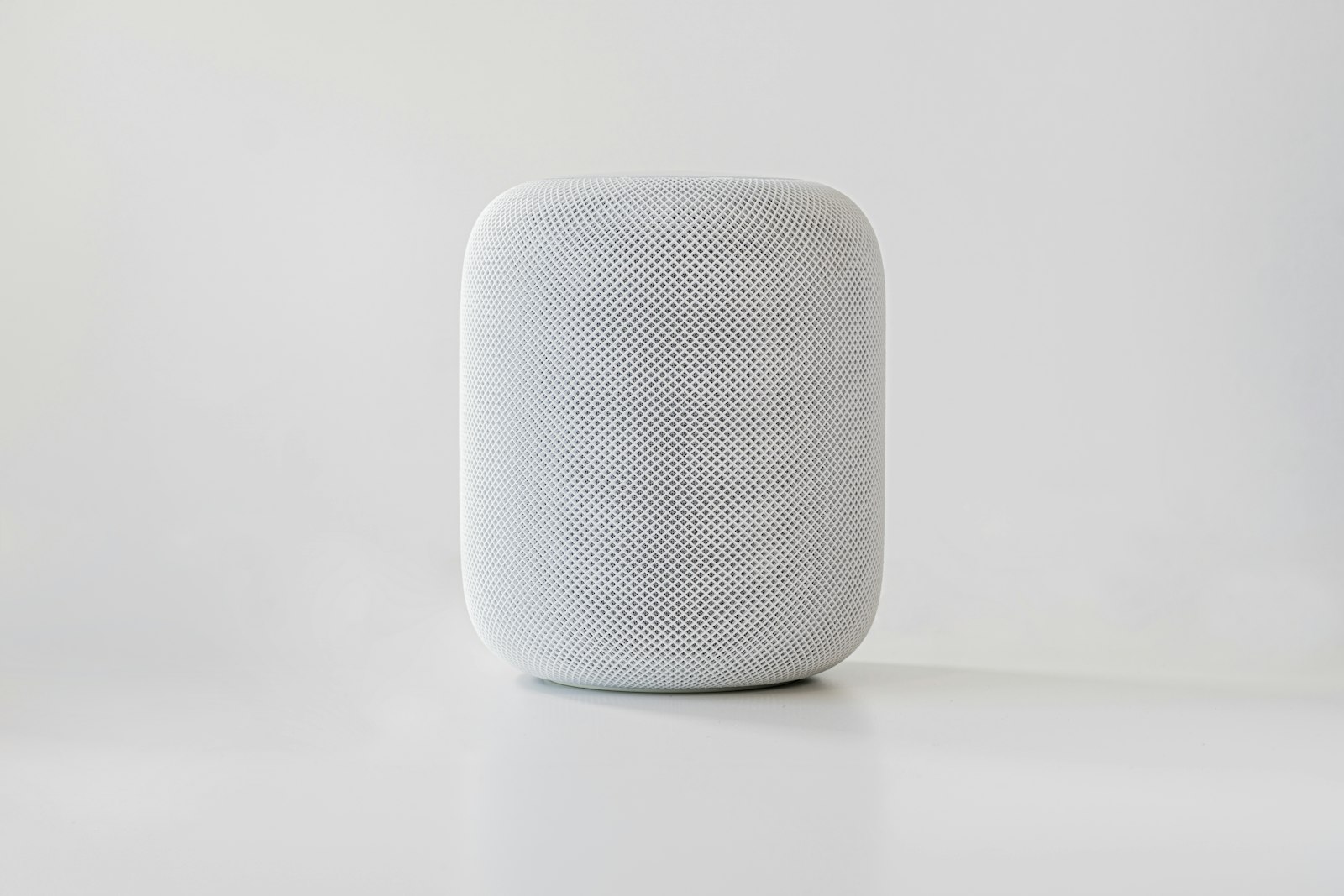 Белая умная колонка Apple на светлом фоне в минималистичной студийной съёмке