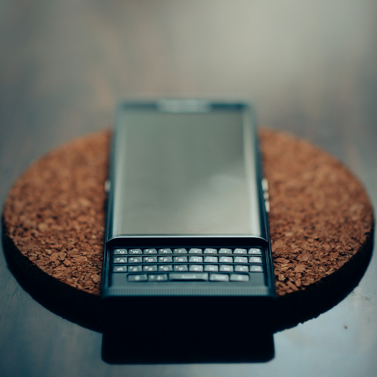 Смартфон с физической QWERTY-клавиатурой на пробковой подставке крупным планом