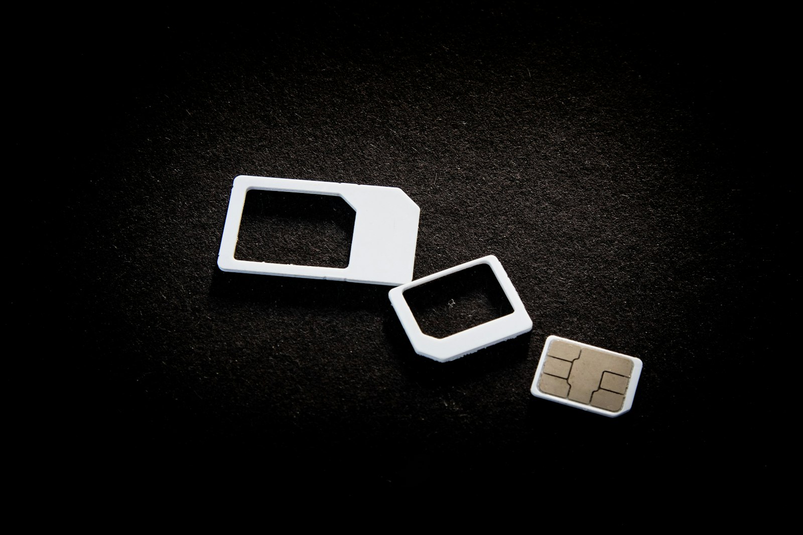 Три SIM-карты разных форматов на чёрном фоне крупным планом